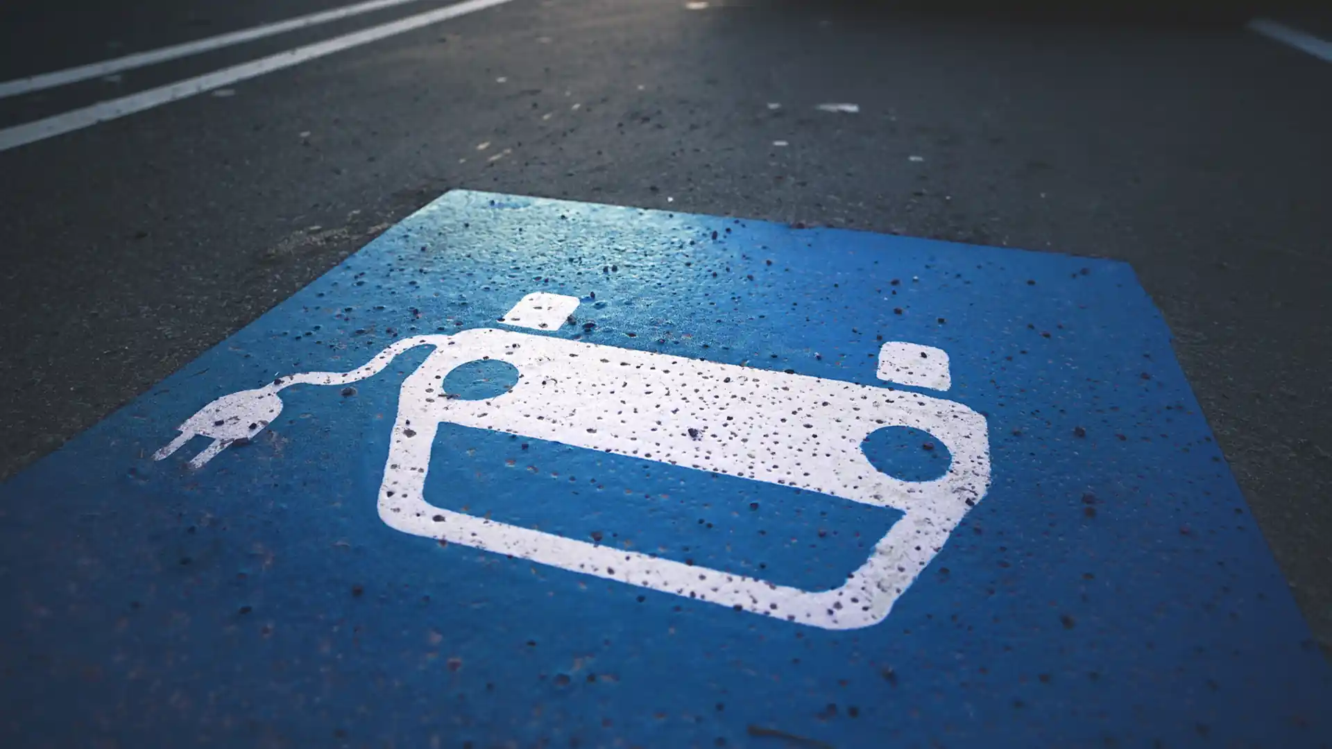 Parkplatz mit Symbol eines Autos mit Kabelstecker auf blau-weiß bemaltem Asphalt