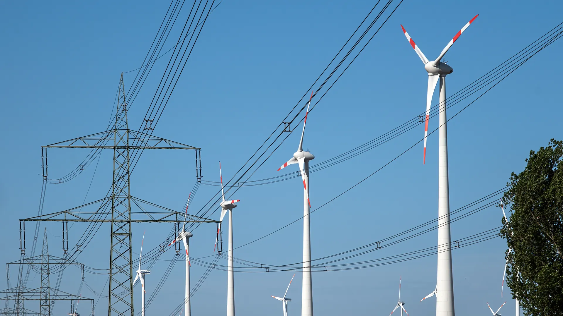 Strommasten mit Stromleitungen und Windkraftanlagen in Deutschland gesehen