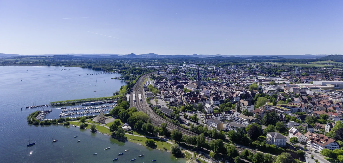 Luftaufnahme von Radolfzell am Bodensee mit Hafen, Bahnstrecke, Wohngebieten und bewaldeten Uferbereichen