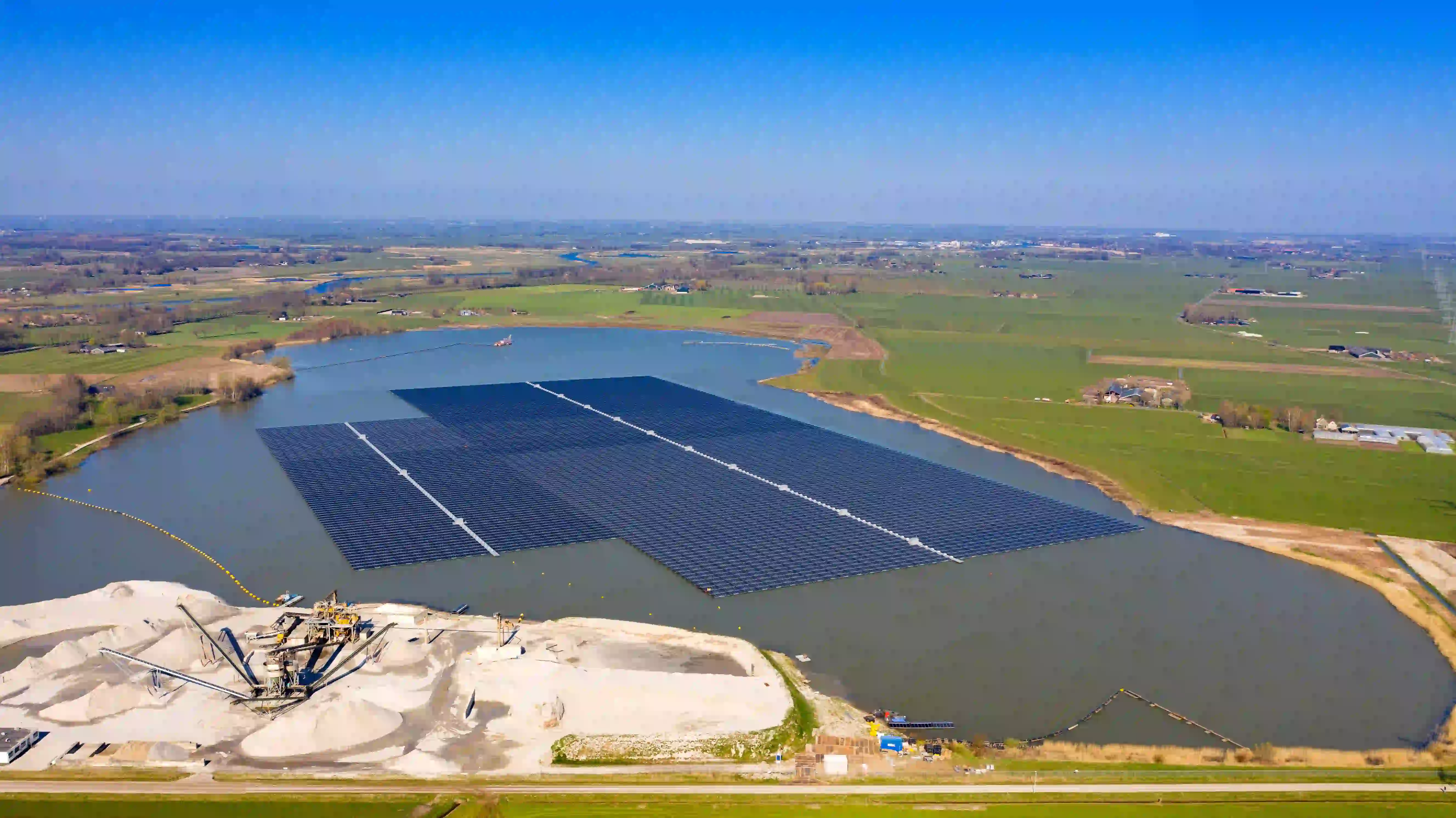 Luftaufnahme: Schwimmende Solaranlage auf See neben Kiesabbau und Agrarlandschaft
