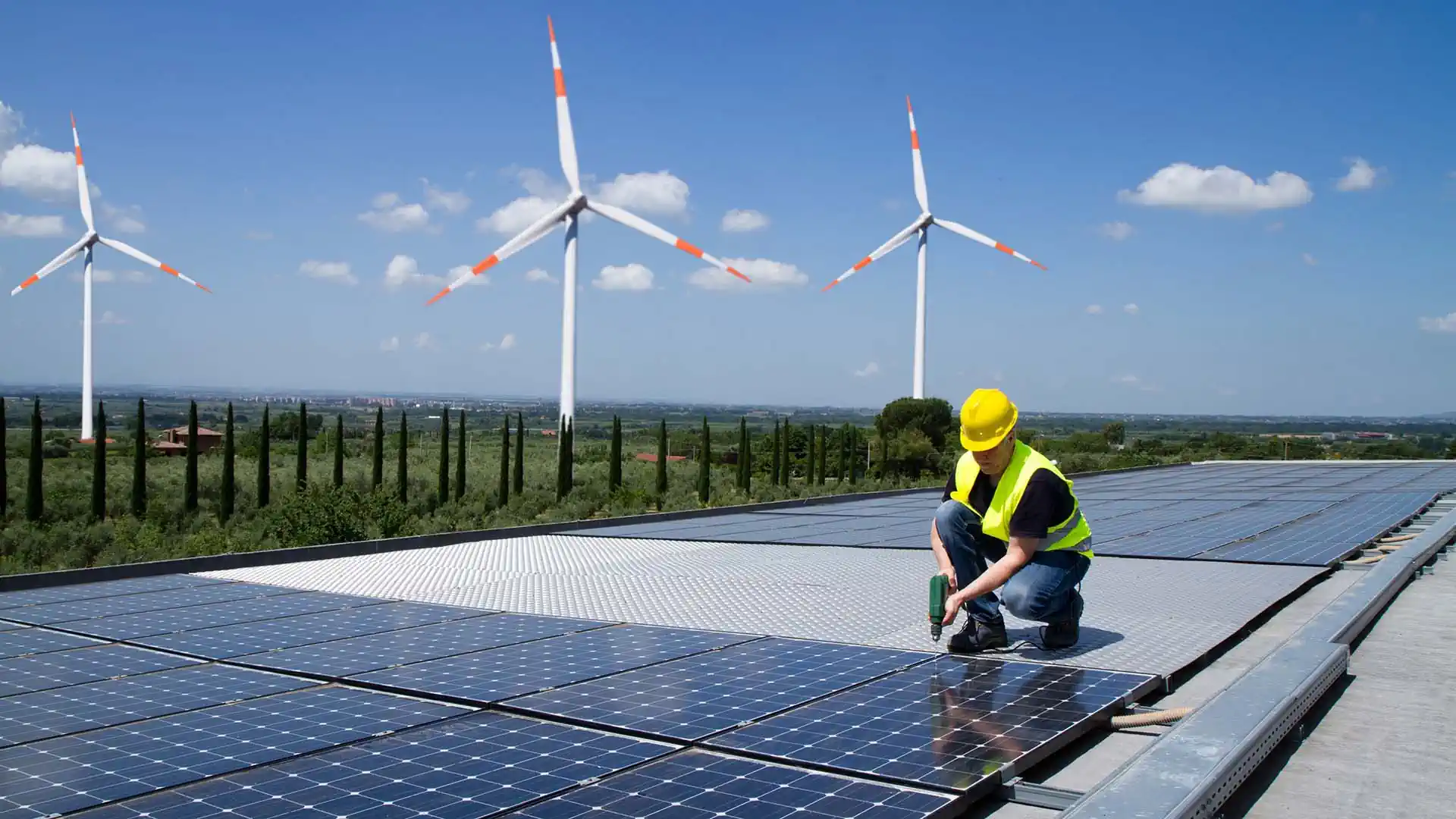 Erneuerbare Energien: Monteur installiert PV-Zellen vor Windanlage
